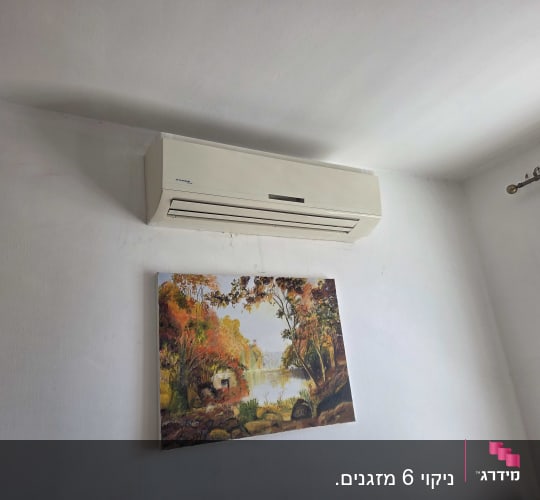 מזגן תלוי על קיר עם תמונה מתחתיו